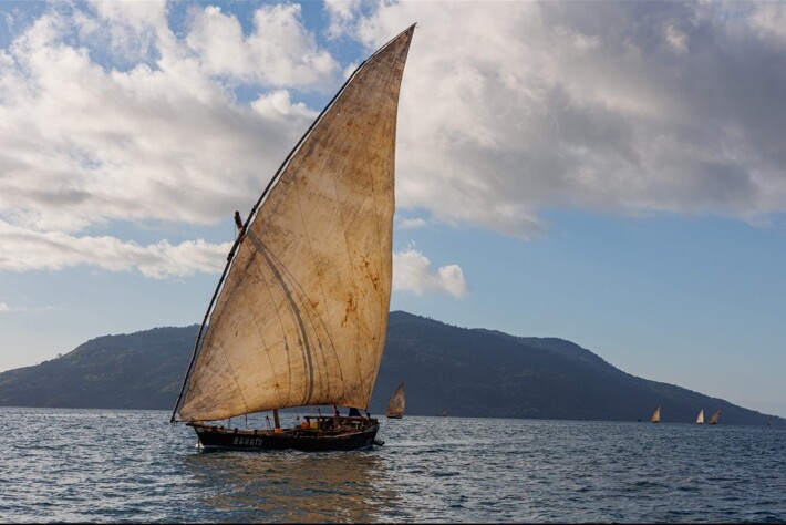 Boutre traditionnel naviguant sous une grande voile devant une île de Madagascar