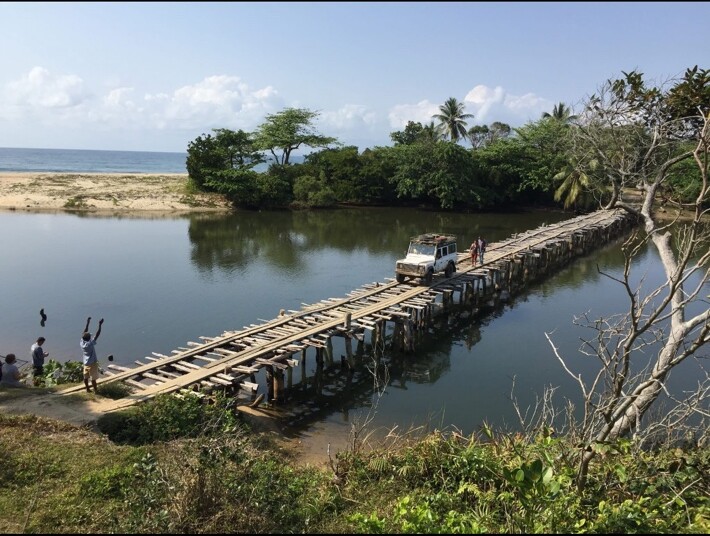 Defender traversant un long pont en bois entre lagune et océan