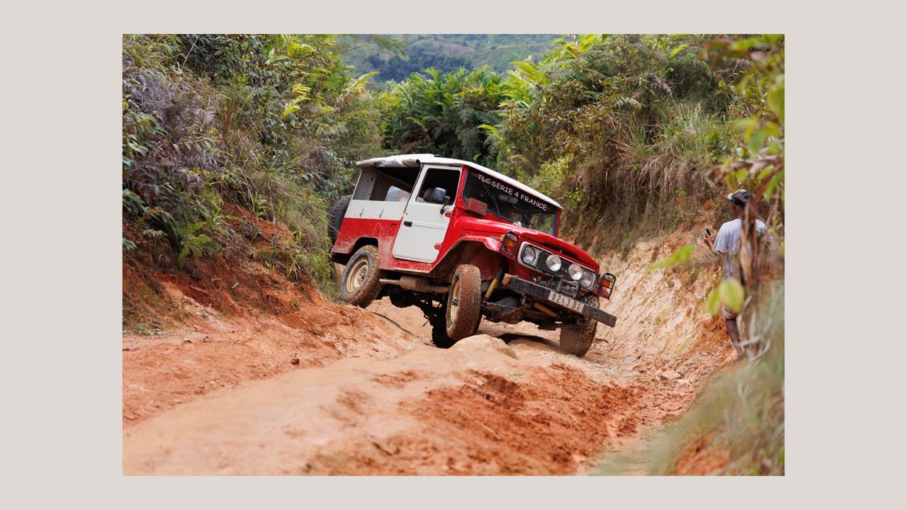 4x4 rouge franchissant une piste profondément creusée à Madagascar