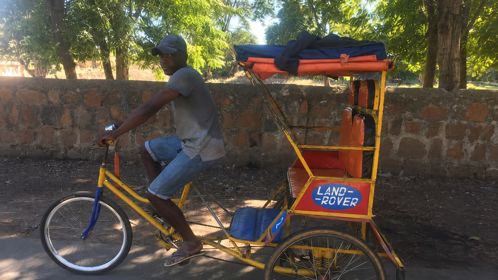 Jeune homme conduisant un taxi-vélo artisanal décoré comme une Land Rover